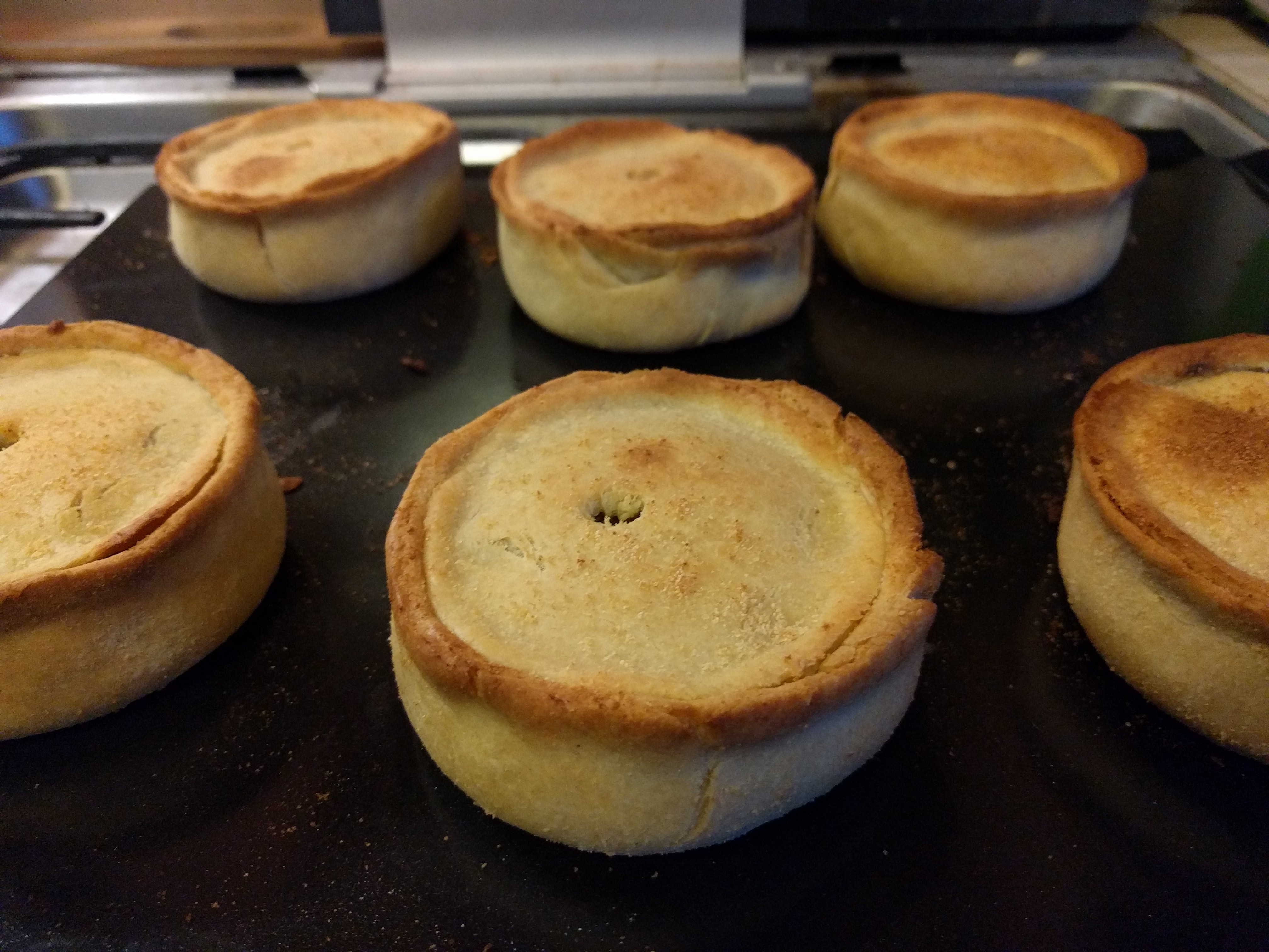 Ready to eat Six scotch pies sitting on a baking tray