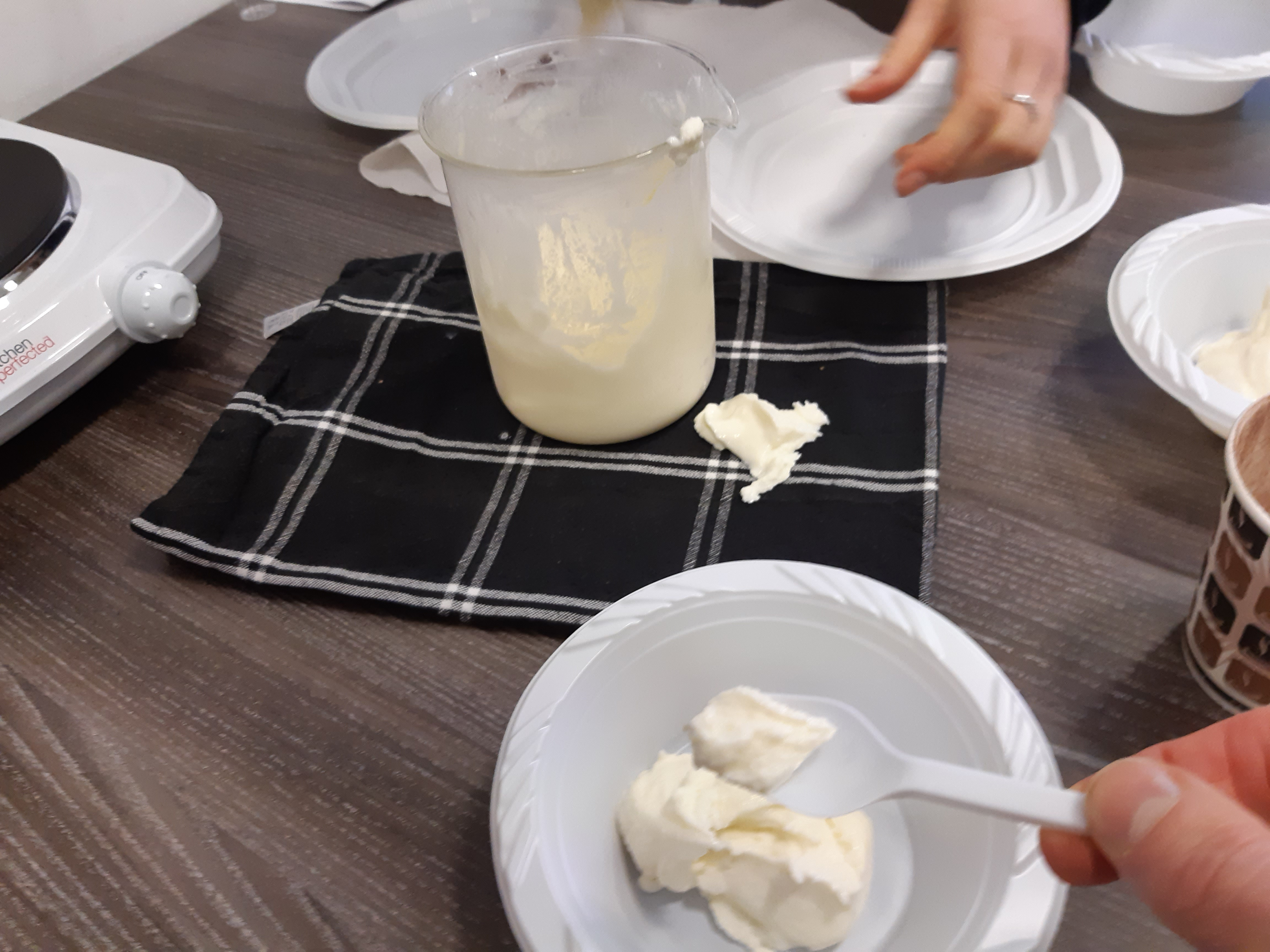 Glass beaker and plastic bowl containing freshly made ice cream.