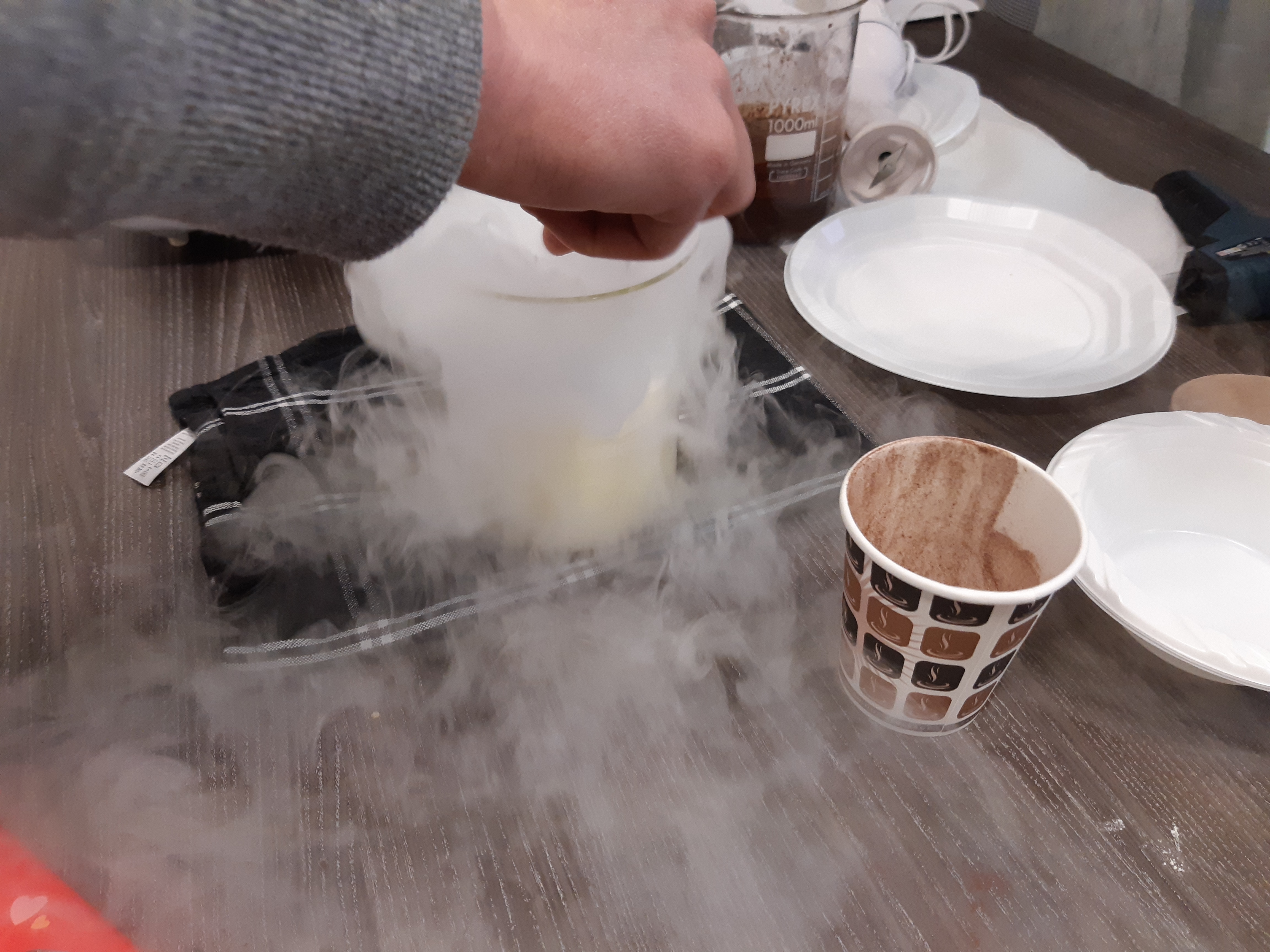 Glass beaker being stirred while white vapour flows out of it.