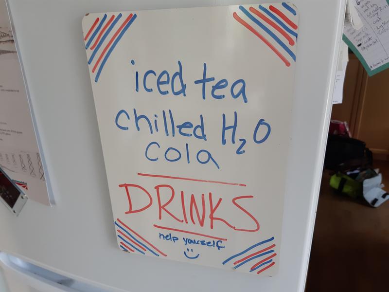 Fridge with notice stating iced tea, cooled water and cola drinks. Help yourselves.