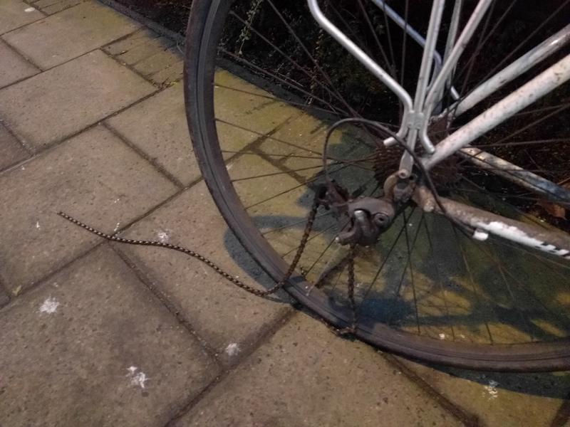 Rear wheel of a bike with a trailing bike chain.